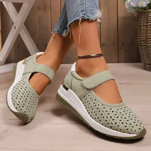 Detail view of sage green perforated wedge shoes with a secure velcro strap.