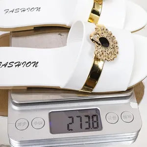 Detailed view of white flat slides with peacock embellishment on a digital scale weighing 273.8g