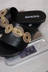 Detail view of black rhinestone flat slide sandal on digital scale weighing 246.2 grams