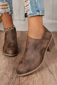 Close-up detail of women's vintage brown distressed chunky heel ankle boots for fall