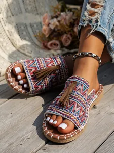 Primer plano de sandalias bohemias con patrones tejidos de colores y borlas de ante marrón