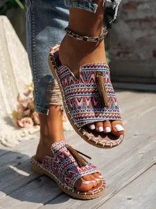 Primer plano de sandalias playeras planas de estilo bohemio con patrones étnicos y borlas