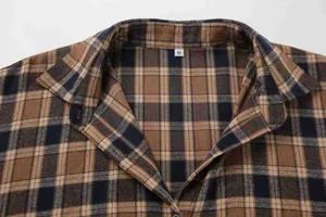 Close-up of coffee brown plaid lapel collar with size M label on loose casual shirt.