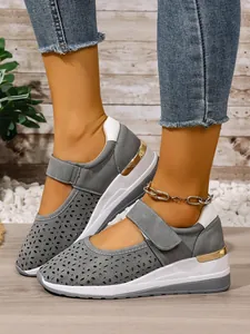 Close-up detail of grey laser-cut wedge sneakers with adjustable hook-and-loop strap