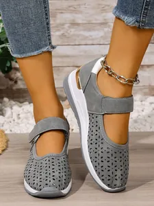Detailed view of grey laser-cut hollow-out walking shoes with velcro strap and thick white sole.