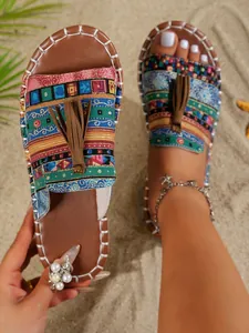 Detalle de sandalias playeras bohemias con estampados coloridos y borlas marrones