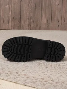 Detail view of the thick lugged black rubber sole of a Martin boot for traction.