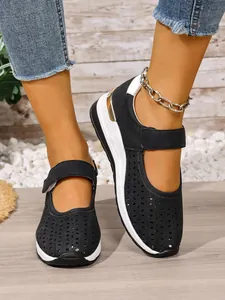 Detail showing breathable laser-cut upper and gold heel accent on black wedge shoes.