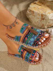 Detalle de sandalias planas bohemias con patrón tejido colorido y borlas para playa