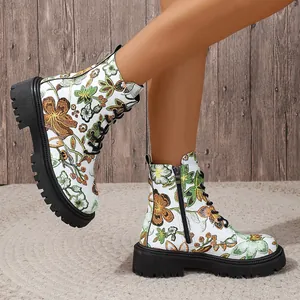 Side view of white floral print lace-up ankle boots with thick black lug soles on model