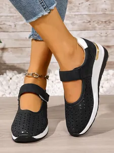 Detail view of black hollow-out Mary Jane shoes with white wedge soles and Velcro straps.