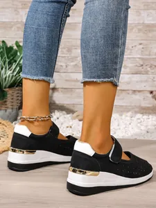 Detail of black hollow-out sport shoes with white wedge sole and velcro strap