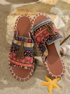 Chanclas planas bohemias con estampado étnico y borla en fondo de arena de playa