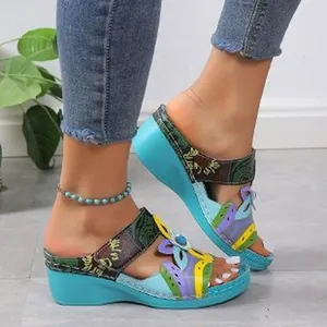 Detailed view of colorful ethnic style wedge sandals featuring floral applique on foot