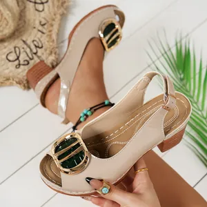 Detailed view of beige patent leather peep toe high heel sandals with gold buckle