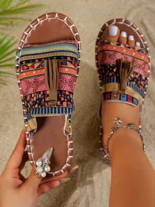 Detalle de sandalias planas de playa estilo bohemio con estampados étnicos y borlas suaves
