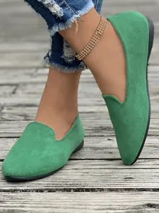 Vista ravvicinata di eleganti ballerine scamosciate verdi a punta tonda da donna su legno