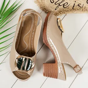 Close-up of nude patent peep-toe sandals with gold buckle and wood-grain block heel.