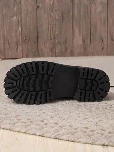 Close-up detail showing the rugged black non-slip rubber lug sole of women's Martin boots