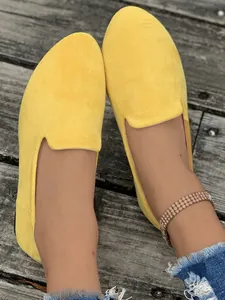 Dettaglio di scarpe basse in camoscio giallo da donna su fondo in legno