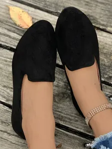 Primo piano di ballerine nere scamosciate a punta tonda da donna su pedana in legno