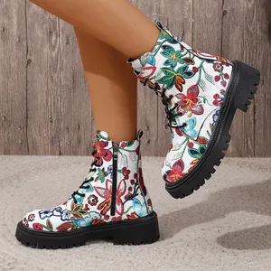 Detail view of women's white high-top Martin boots with colorful floral embroidery.