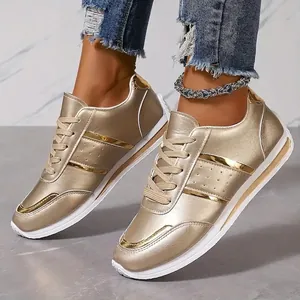 Detail of gold metallic sneakers for women with white soles and laces worn by a model.