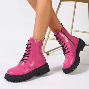 Vue détaillée de bottines de combat rose vif en cuir verni à plateforme sur modèle