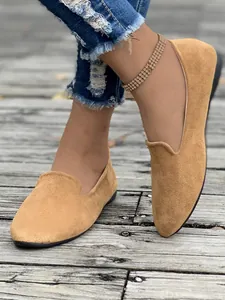 Mocassini piatti in camoscio color cuoio su pedana in legno rustico, dettaglio moda autunno