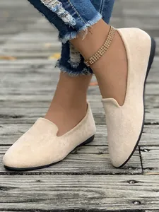 Dettaglio ravvicinato di eleganti mocassini da donna in camoscio beige e piatti