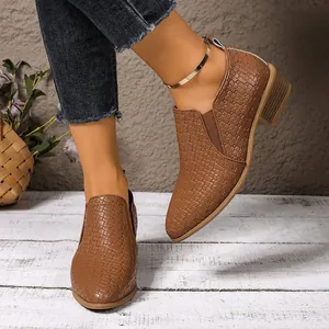 Detail view of women's brown pointed toe ankle boots with woven texture and chunky heel