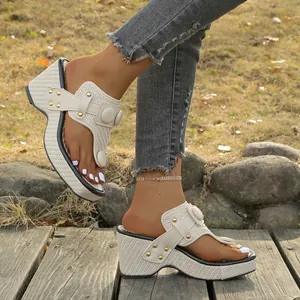 Close-up of stylish women's wedge thong sandals with woven texture and gold studs.