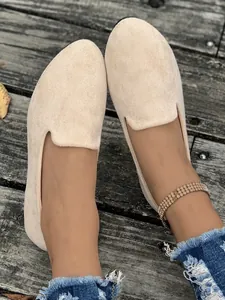 Dettaglio di scarpe basse beige in velluto da donna con punta tonda su legno