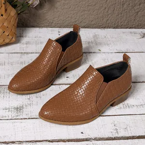 Macro shot of brown pointed-toe loafers with an elegant woven embossed texture finish
