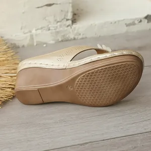 Detailed view of the textured sole and wedge heel of gold floral beach sandals
