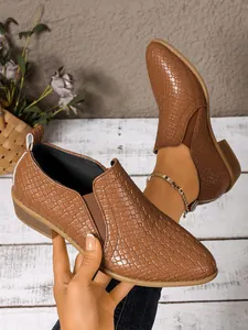Detailed view of brown textured leather pointed toe ankle boots with low chunky heels.