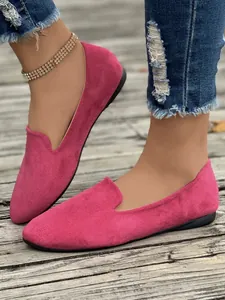 Scarpe piatte da donna in camoscio magenta abbinate a jeans strappati su legno