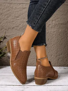 Detail view showing the woven texture and fit of brown pointed-toe chunky heel boots