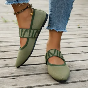 Close-up detail of green breathable fly-knit flat shoes worn on a wooden deck.