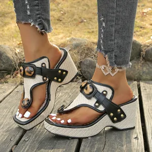 Detail of wedge thong sandals featuring leopard print accents and gold studs on a wooden deck.