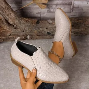 Detailed view of women's pointed-toe loafers with woven texture being worn