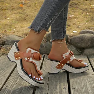 Close-up of woven wedge thong sandals with brown leather straps and metal studs