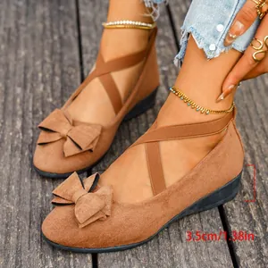 Detail of brown suede wedge shoes for women with bow accent and 3.5cm heel height.