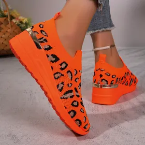 Detail of orange leopard print fly-knit sneakers with wedge heel and platform sole.