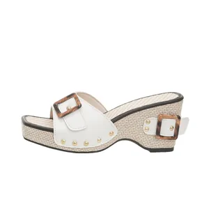 Detail of summer wedge sandal with woven straw texture and leopard print buckles.
