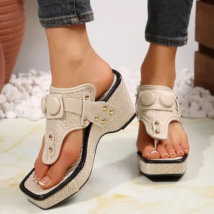 Close-up of beige woven platform thong sandals with gold metal studs and wedge heels.