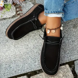 Close-up view of black ethnic loafers featuring white stitching and thick wood grain sole