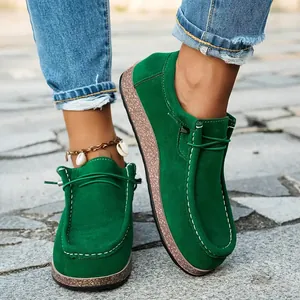 Close-up of green suede loafers with white stitching and thick cork-textured soles