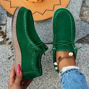 Detail of green suede loafers with wood-grain thick sole and white stitching
