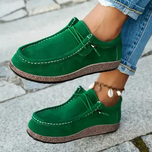Close-up of green suede loafers with white stitching and textured cork platform sole